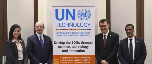 two men and a woman from UNIDO posing next to UNTBLDCs banner during the 9th governing council session of the UN Technilogy bank for the least developed countries