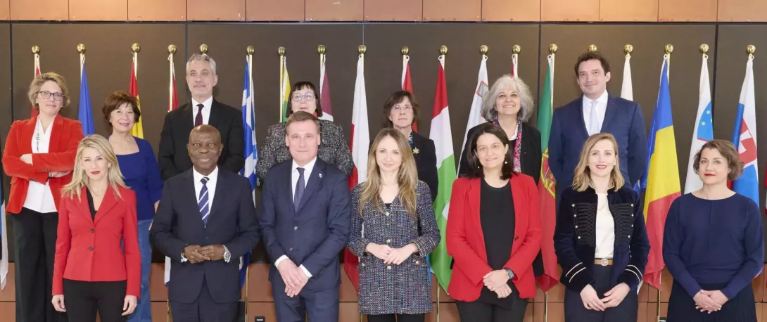 Group photo of professionals standing in front of international flags