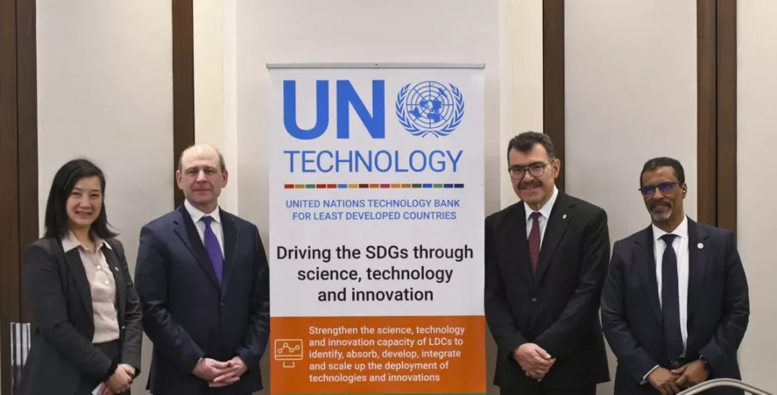 two men and a woman from UNIDO posing next to UNTBLDCs banner during the 9th governing council session of the UN Technilogy bank for the least developed countries